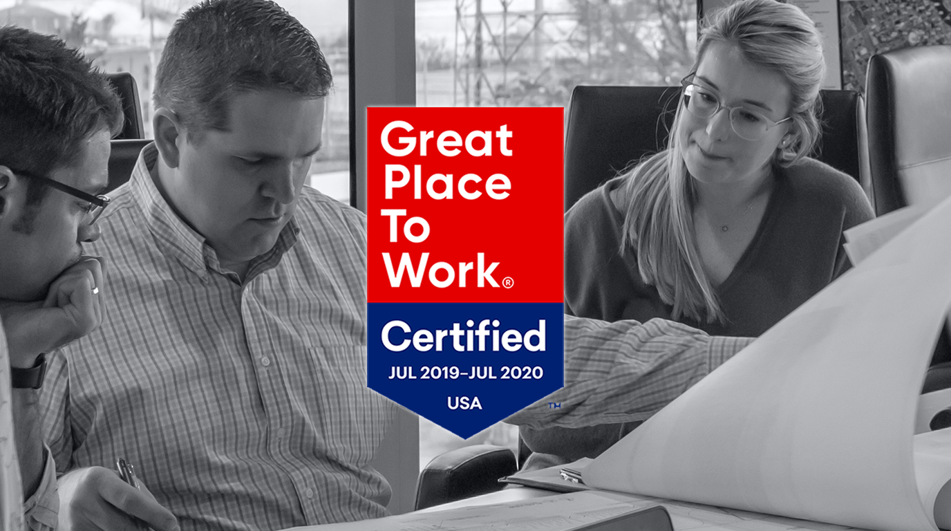Great Place to Work Certified logo and background image of people looking at paper on table